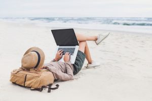 Resting woman using laptop on a beach