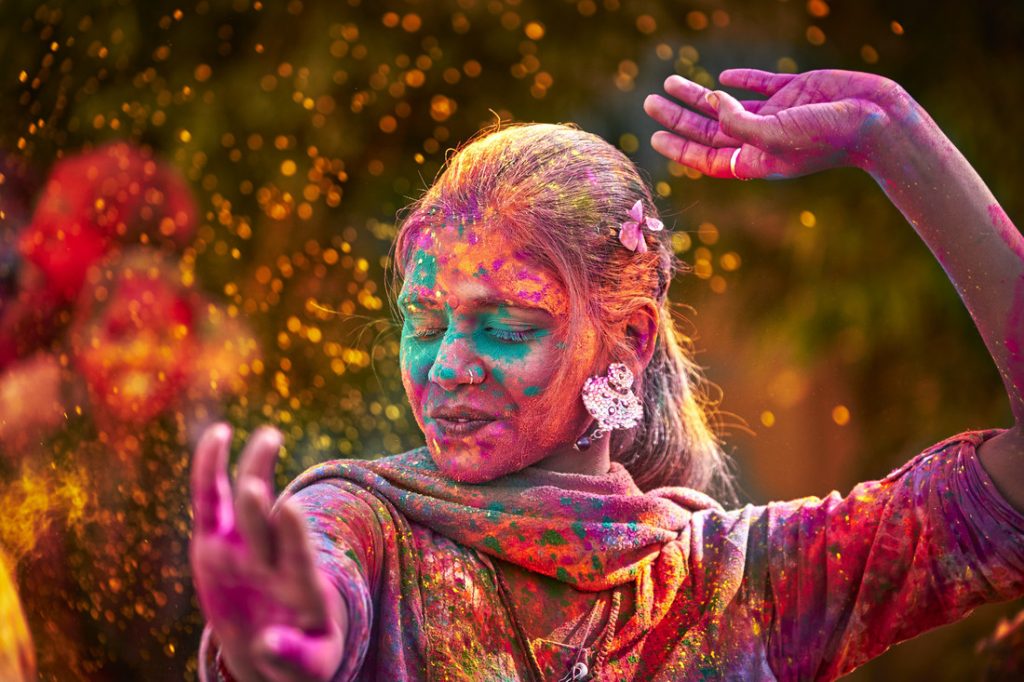 Portrait Of Young Indian Woman With Colored Face Dancing During Holi