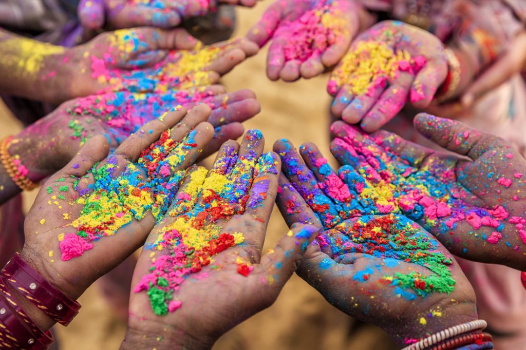 Group of Indian children playing happy holi in Rajasthan, India. Indian children keeping their hands up and showing colorful powders. Holi, the festival of colors, is a religious festival in India, celebrated, with the color powders, during the spring.