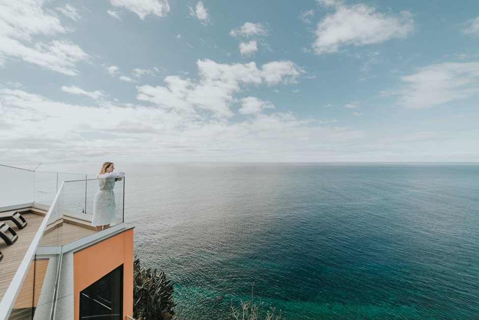Woman looking out to sea on the balcony of a hotel in Madeira sunny