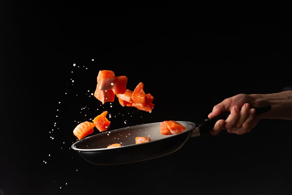 pieces of salmon being cast up from a frying pan