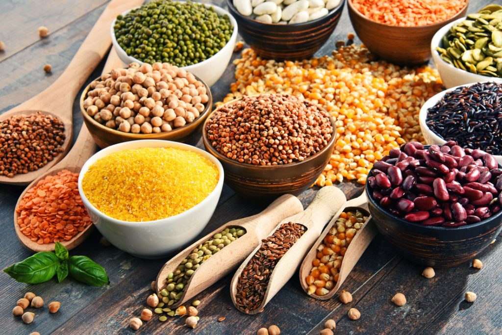 Bowls and wooden spoons filled with seeds, nuts and legumes for the pegan diet