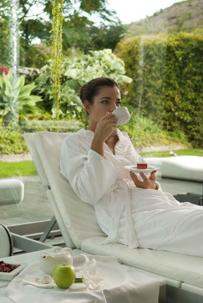 woman in white bathrobe enjoying a cup of tea at the Sha Wellness Clinic