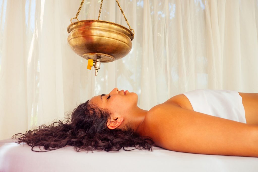 Young woman receiving a traditional Ayurveda treatment for migraines.